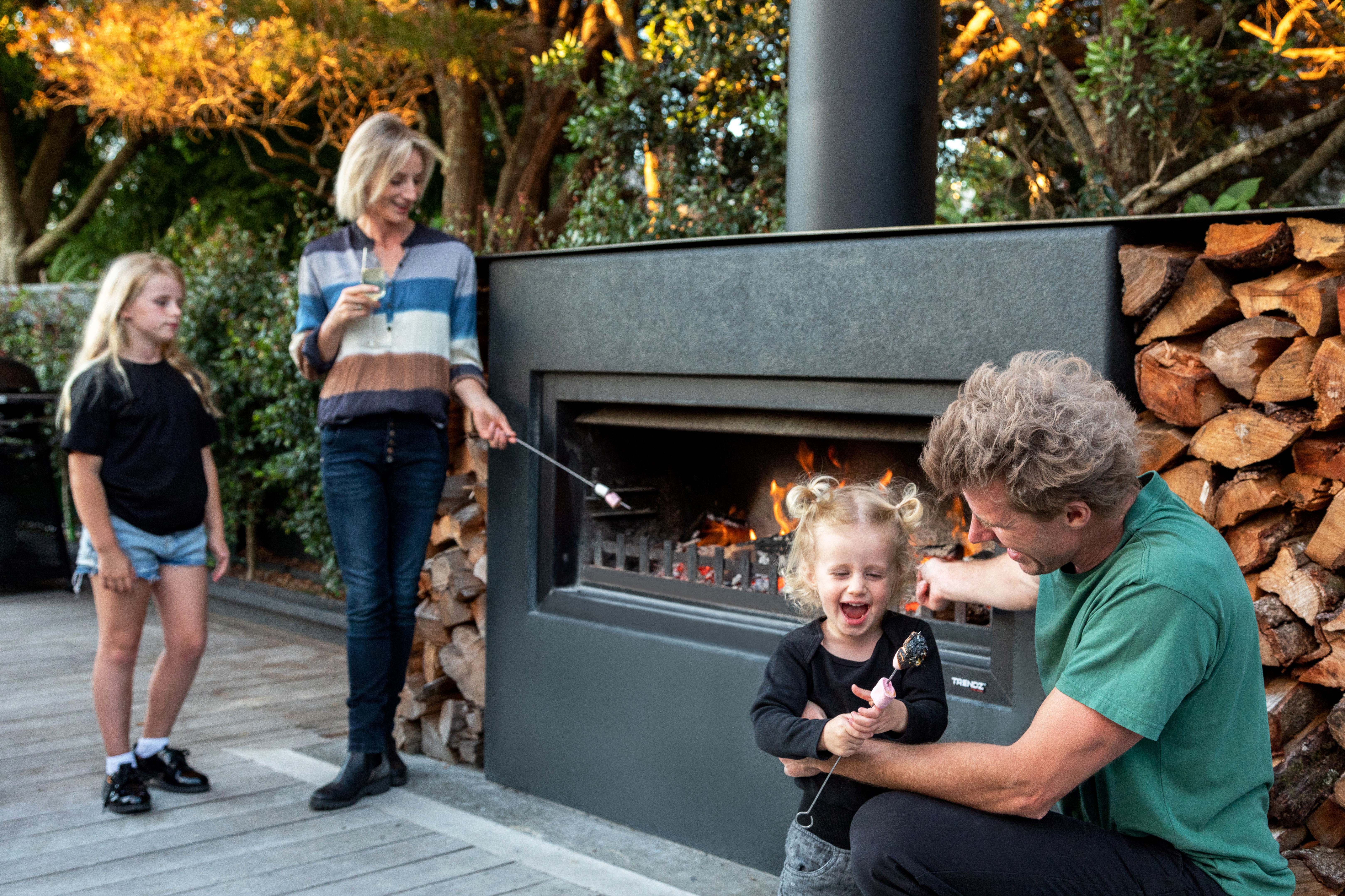 burton outdoor fireplace plaster and paint finish with corten steel woodboxes with a family around the fire