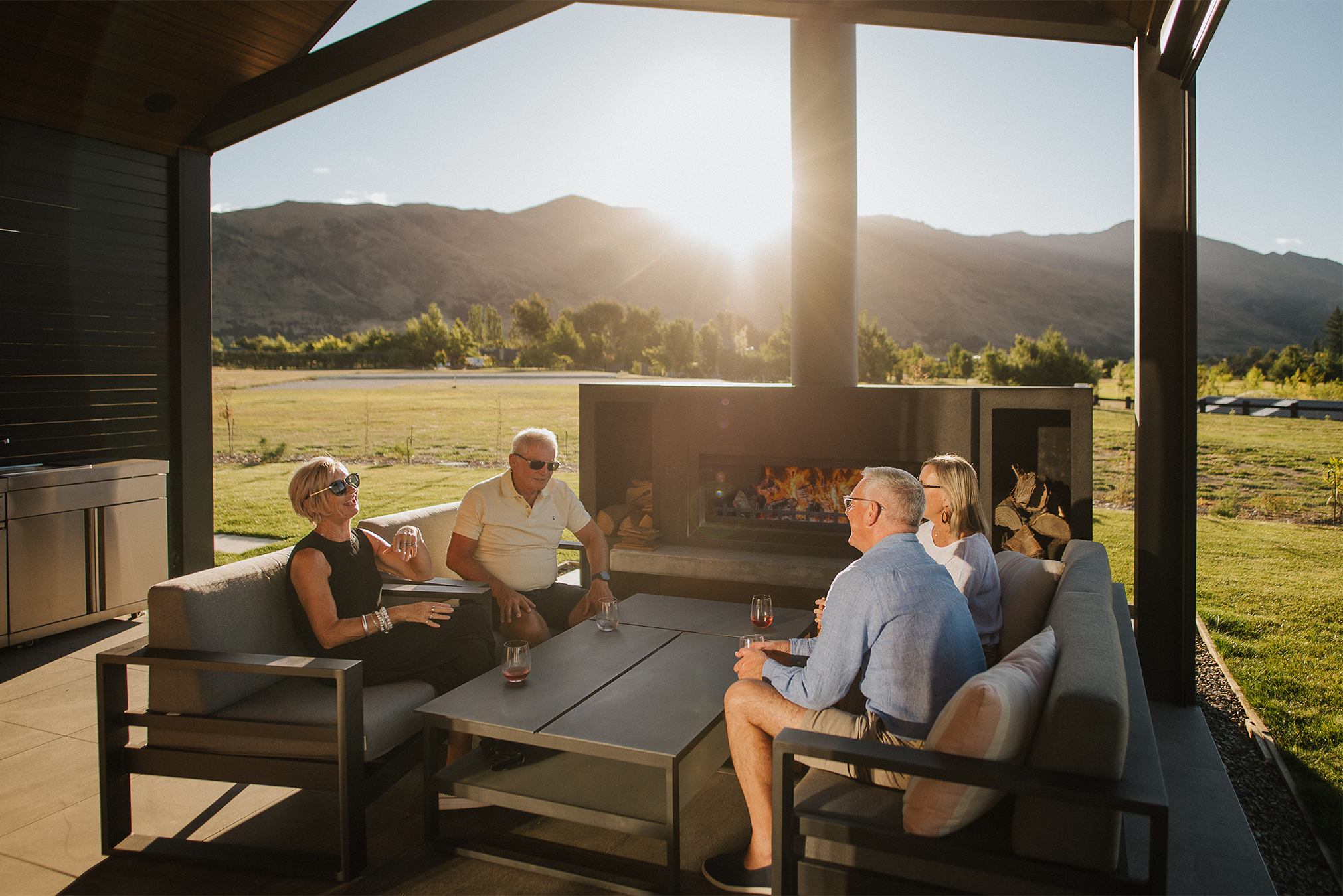 friends sitting around a Burton outdoor fireplace in the sun